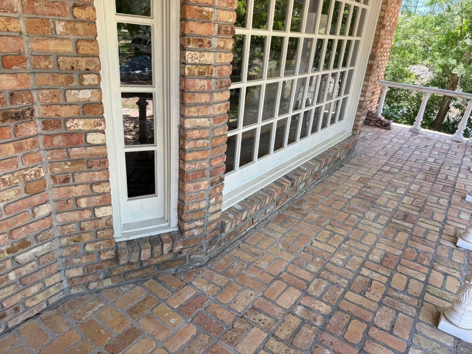Rebuilt brick course beneath a bay window with tight, matched mortar joints