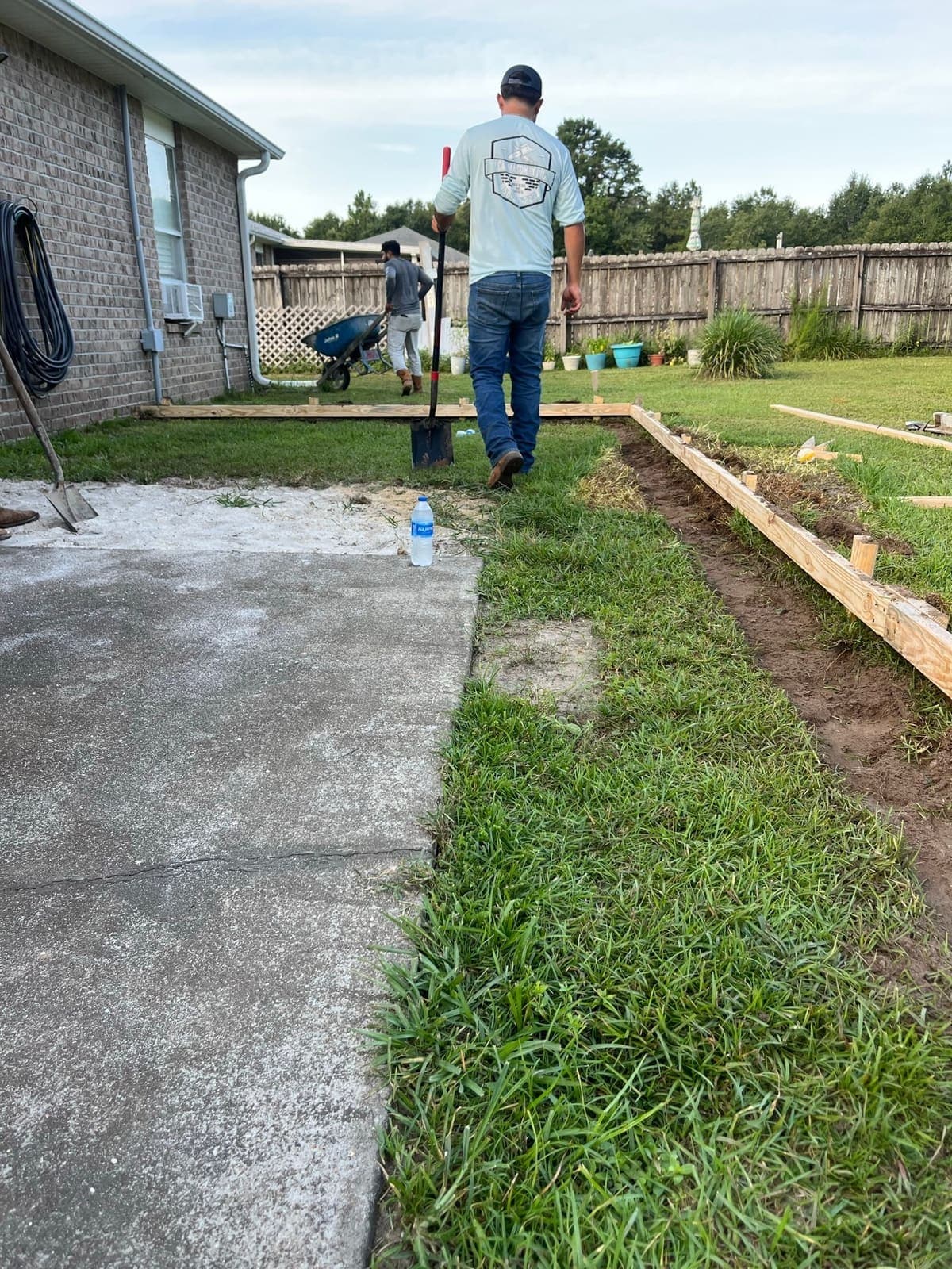 The original weathered patio slab, stained and cracked with grass growing over its edge