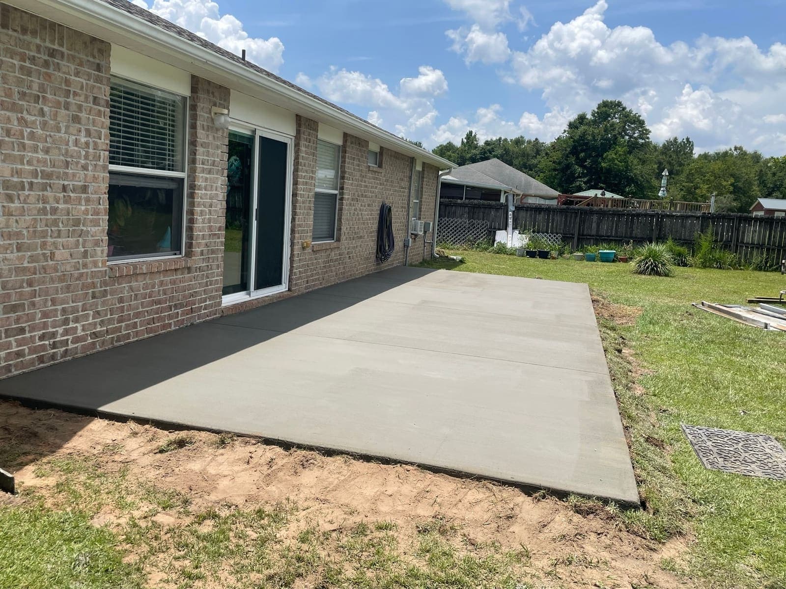 The finished patio slab in clean new concrete, extended out from the back door of the brick house